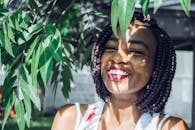 阳光明媚的户外，一位快乐的女子在郁郁葱葱的绿叶间微笑