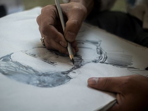 Free Detailed close-up of hands sketching a portrait with pencil on paper, highlighting artistic process. Stock Photo