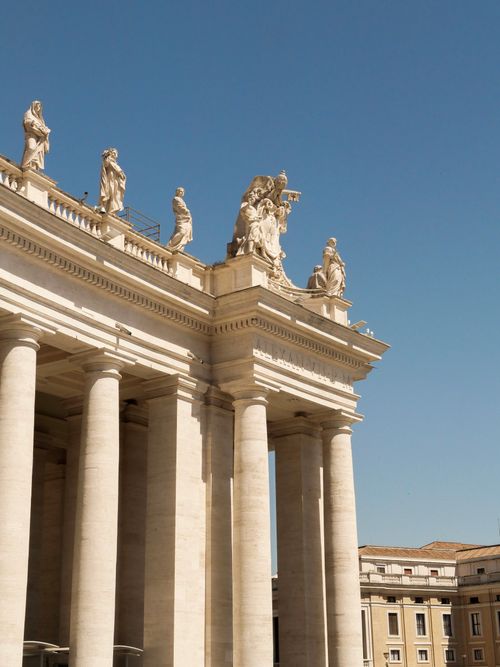 Free Detailed view of neoclassical columns and sculptures against a clear sky in Vatican City. Stock Photo