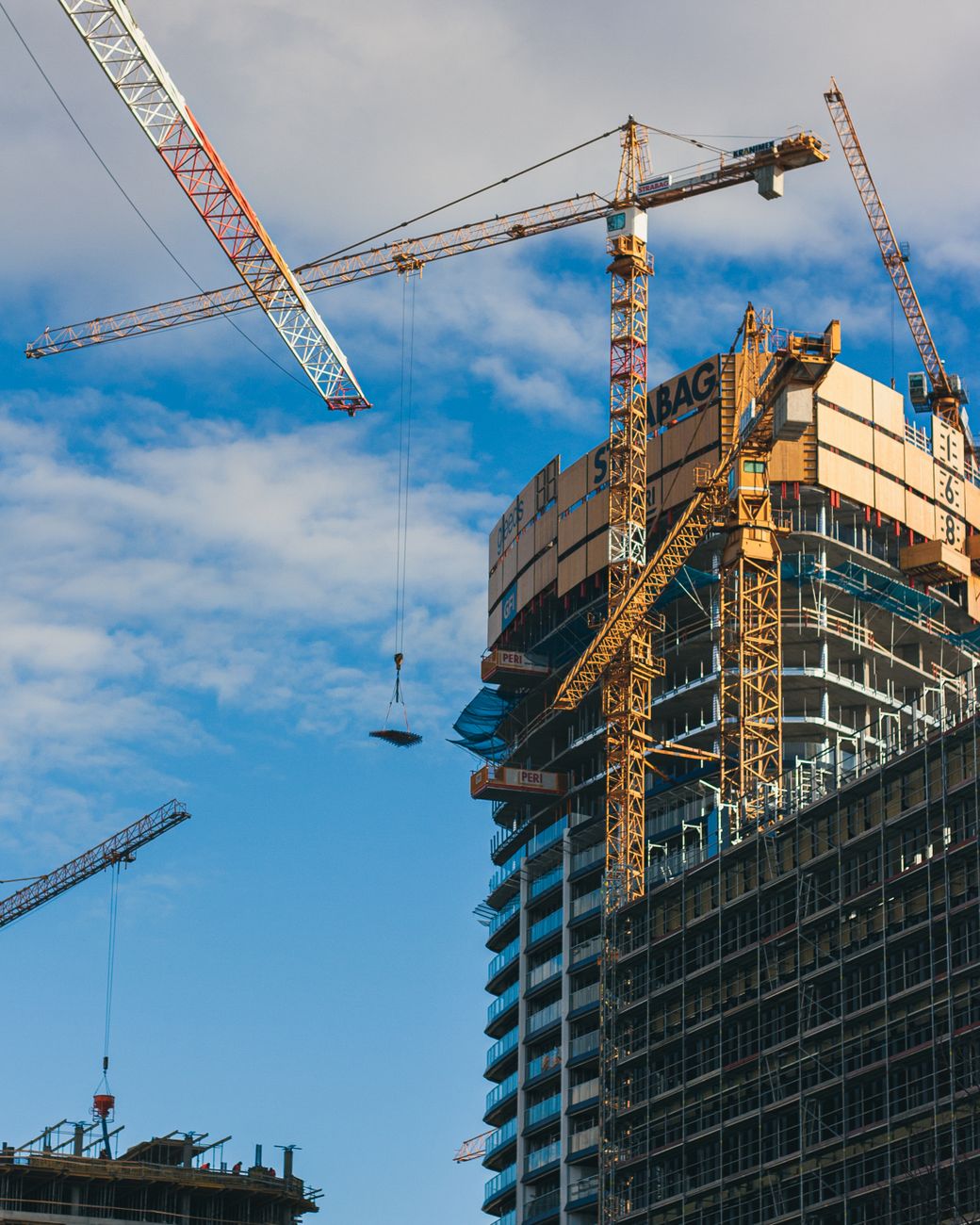 High-rise building construction with cranes in Bratislava, Slovakia under a clear blue sky.