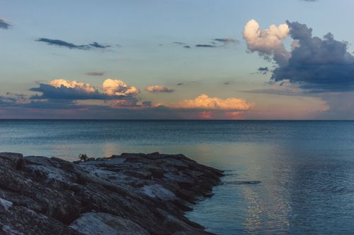 Free Calm sea with dramatic clouds and rocky shore during sunset. Stock Photo