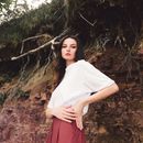 Woman in White Shirt and Red Skirt Standing on Brown Rock