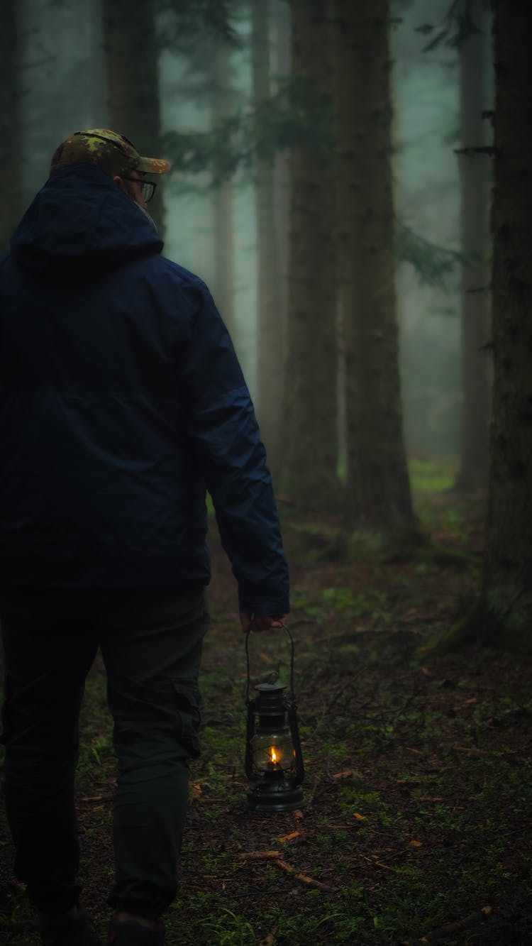 Man Walking In The Woods Carrying A Lantern