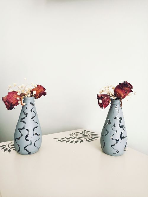 Free Minimalistic display of dried red roses in patterned vases on a decorated table. Stock Photo