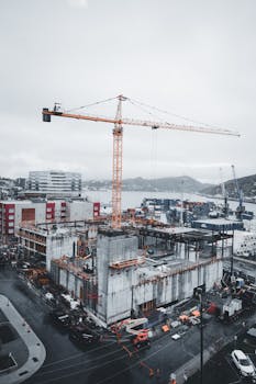 Aerial view of an urban construction site with a tower crane on an overcast day.