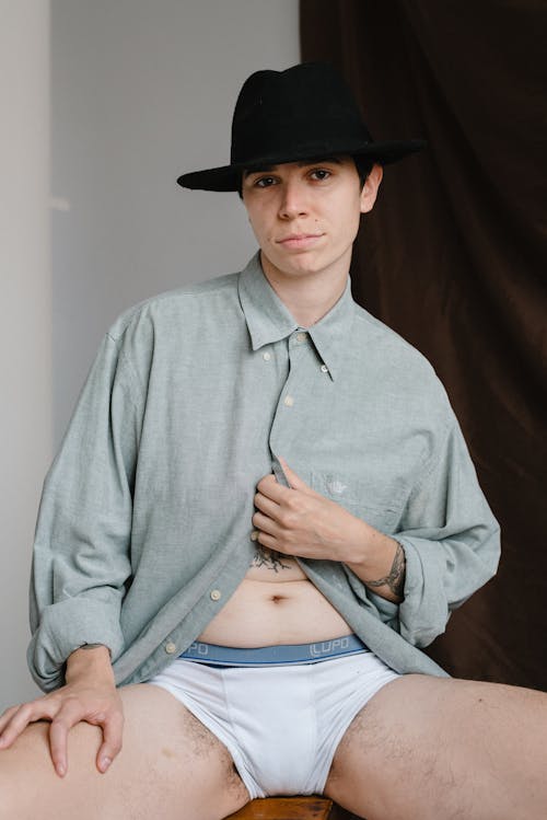 A Man in Blur Dress Shirt and White Brief Wearing Black Hat