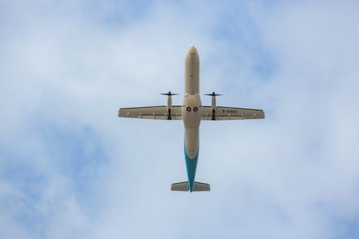 A passenger airplane viewed directly from below against a clear blue sky.