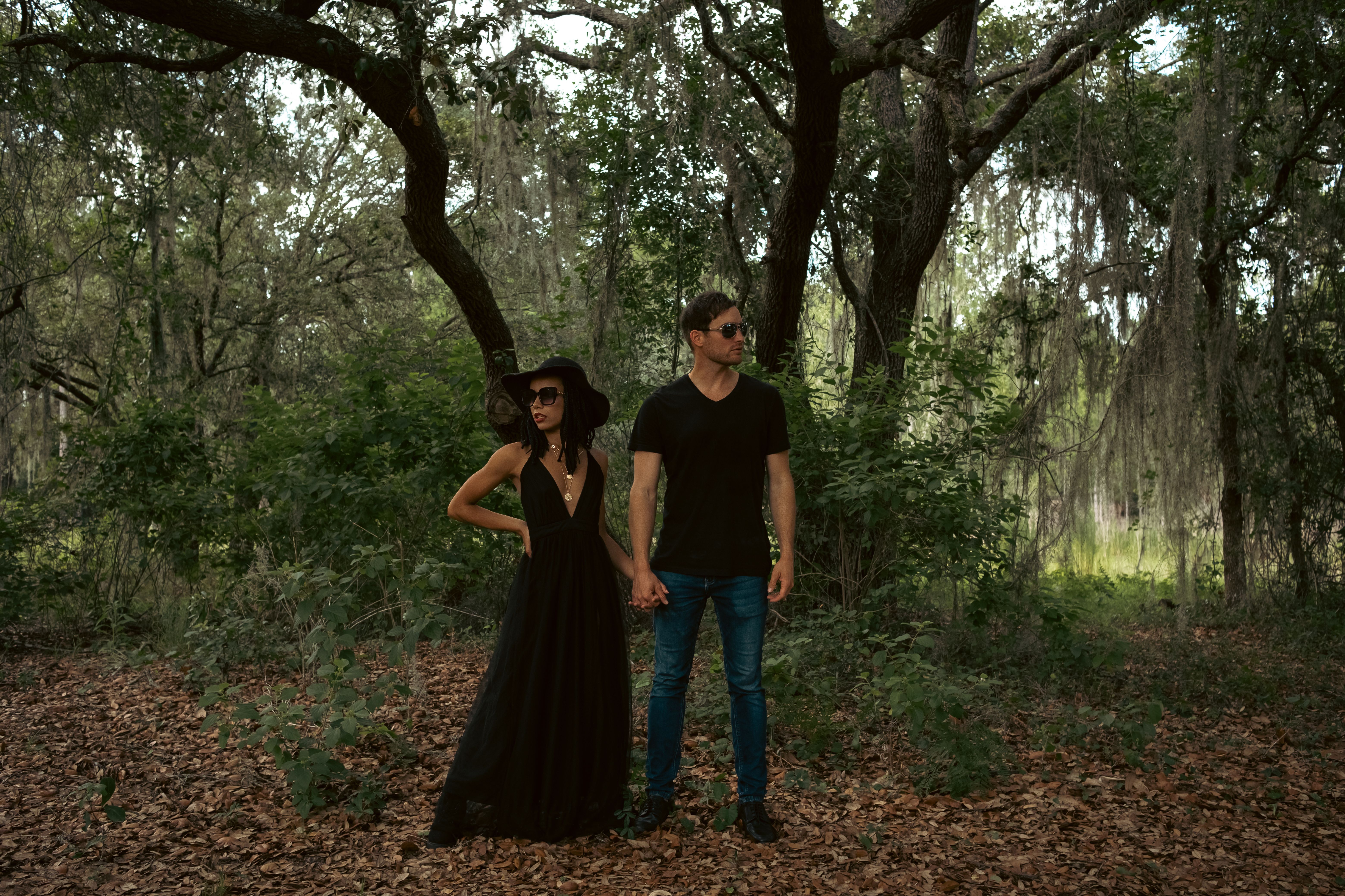 Man in Black Shirt Holding Hands with a Woman in Black Gown in the ...