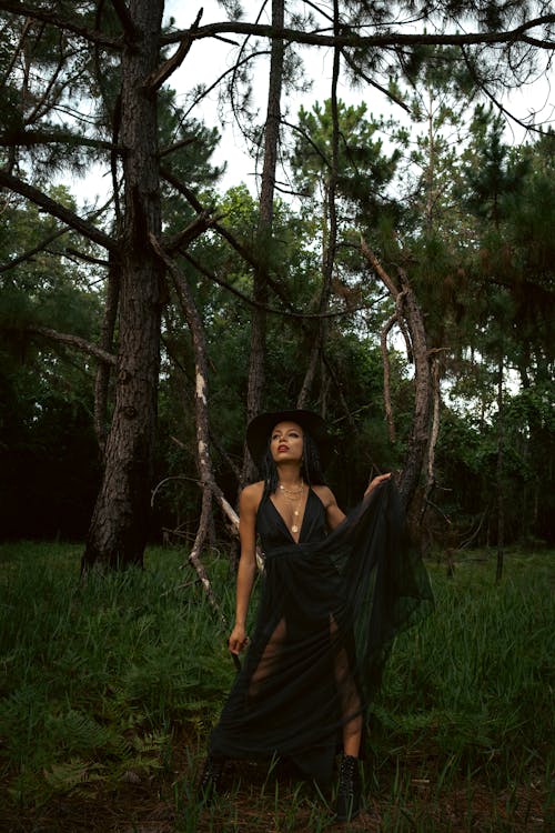 Woman in Black Dress Standing on Green Grass Field