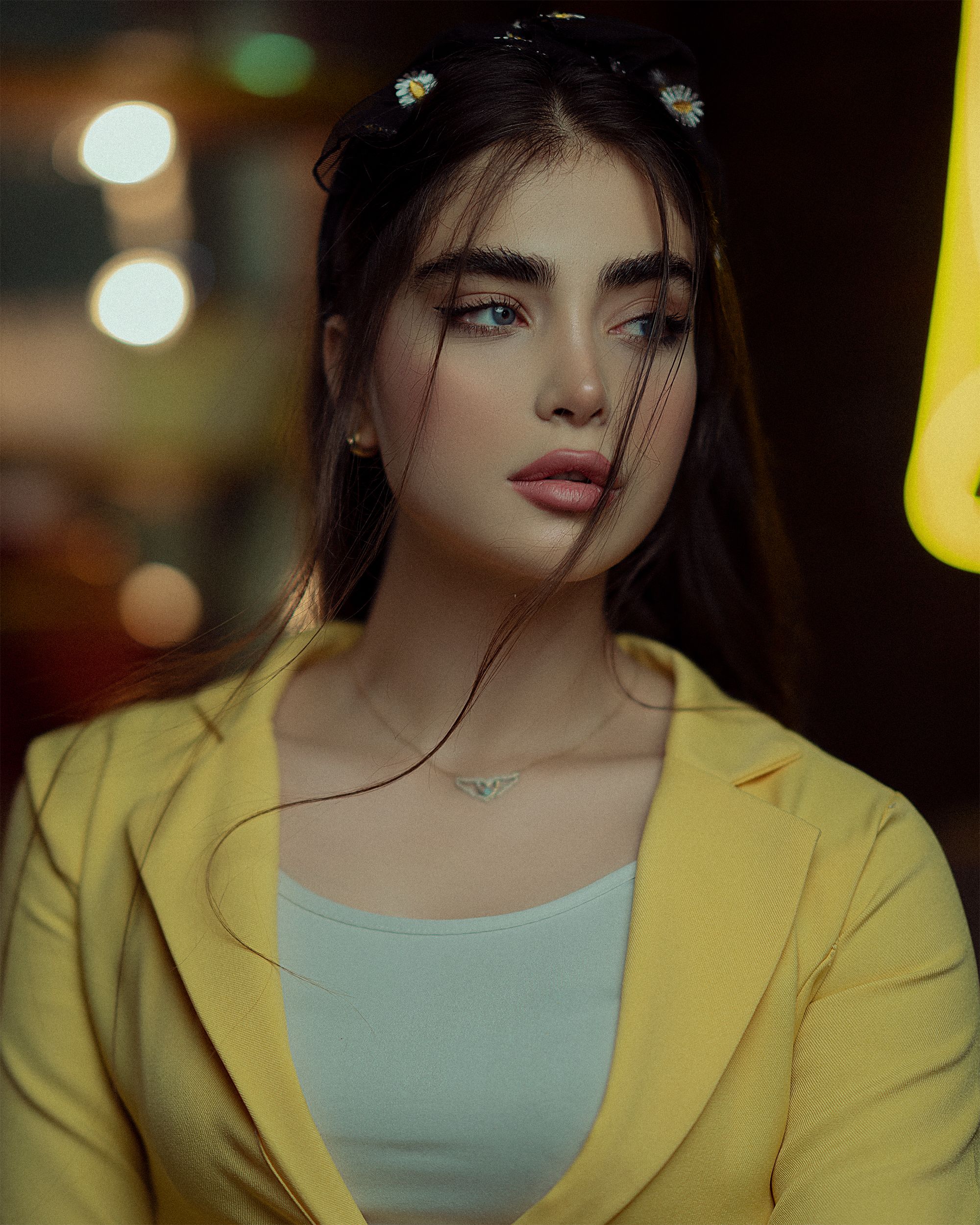 Stylish woman in a yellow blazer looks away, exuding elegance and sophistication.