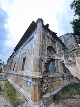 Low angle view of an ancient stone building with intricate details against a cloudy sky.