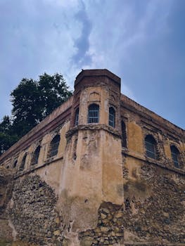 A low-angle view of a weathered stone building under a moody sky.