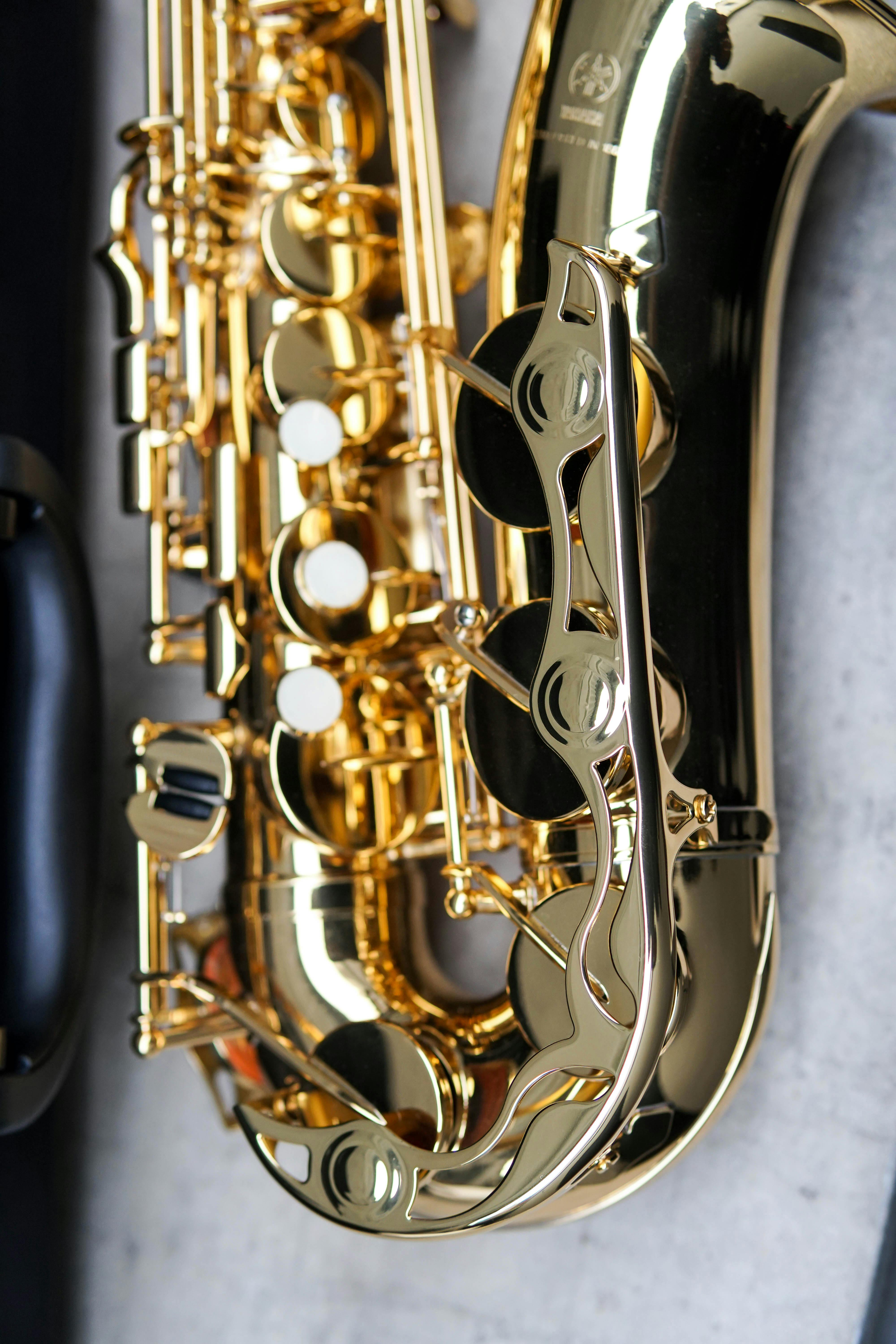 Detailed close-up of a shiny gold saxophone against a concrete backdrop. Perfect for music-related themes.