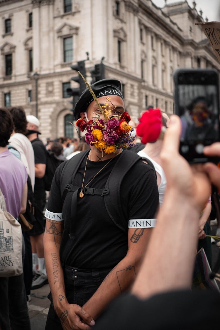 A Man In Black Shirt With Bunch Of Flowers On His Face