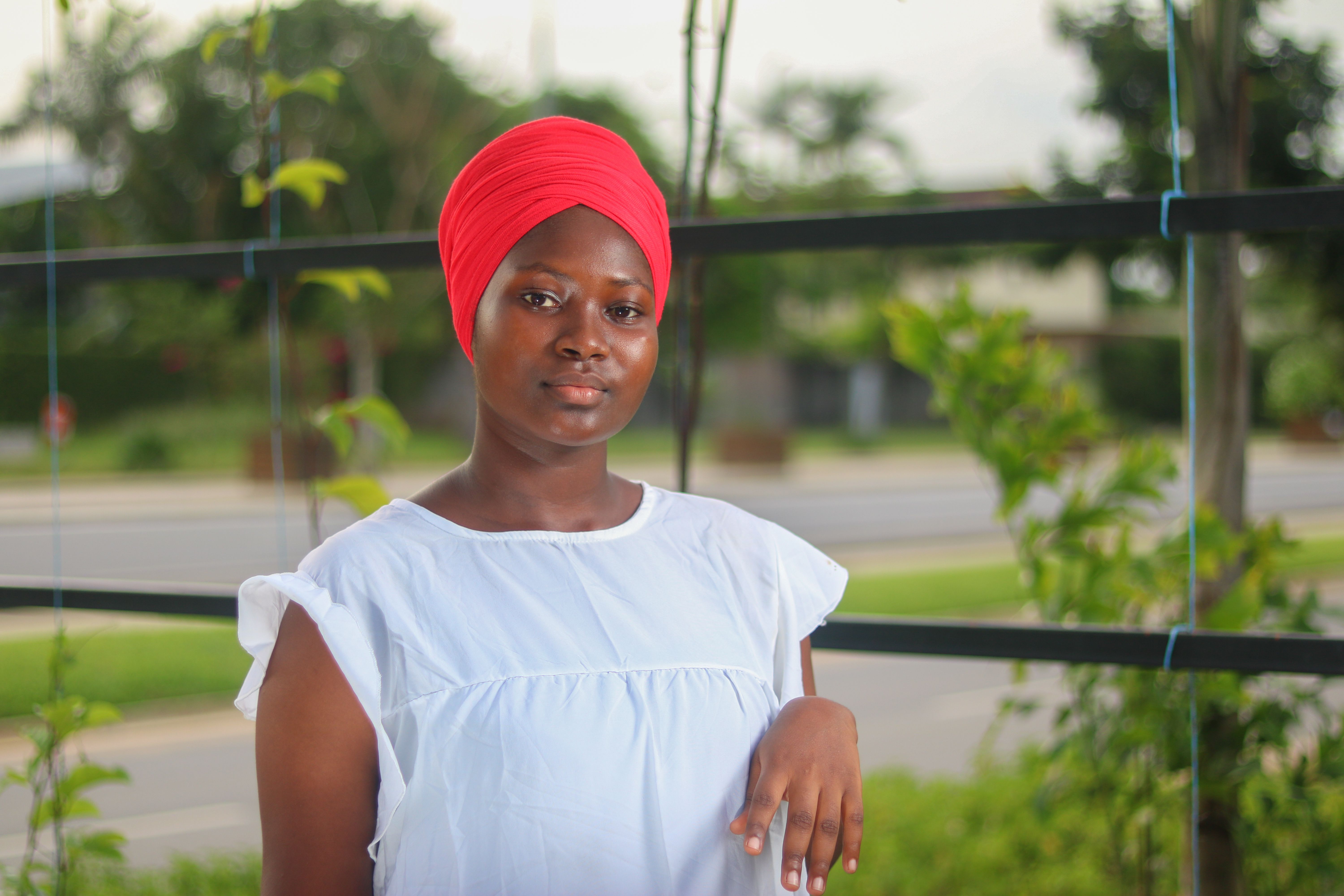A woman in a red headscarf standing outdoors in Abidjan.