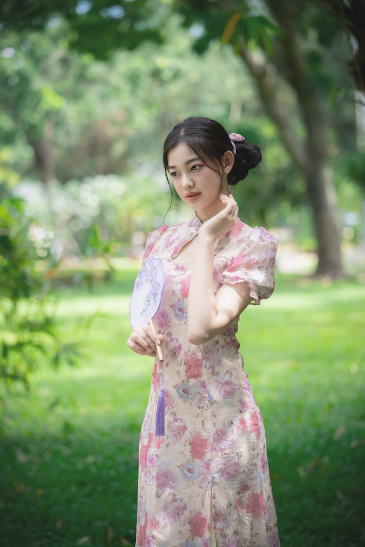 A Woman In A Floral Dress Holding A Fan