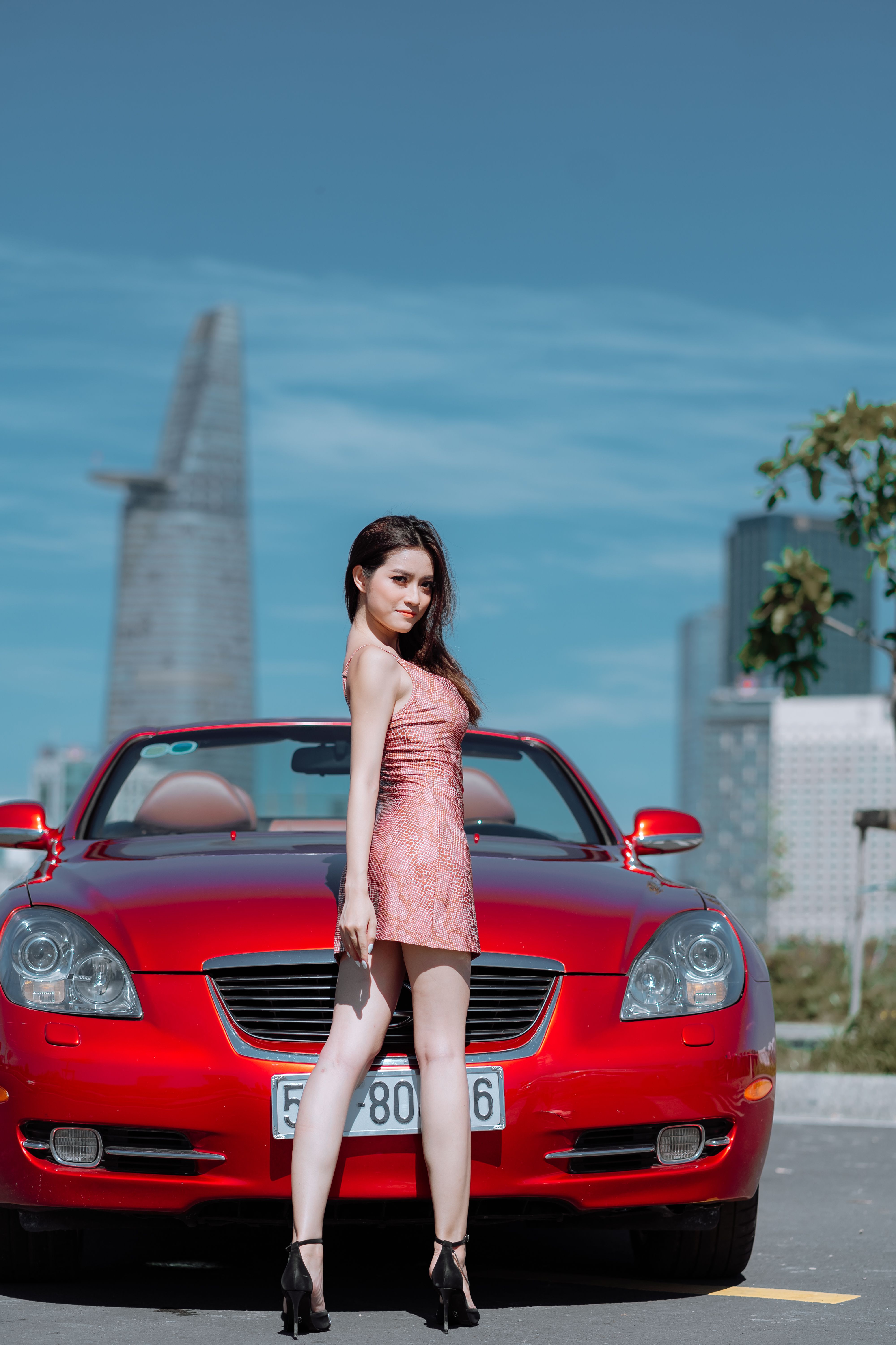 Woman in Pink Dress Standing Beside Red Car · Free Stock Photo