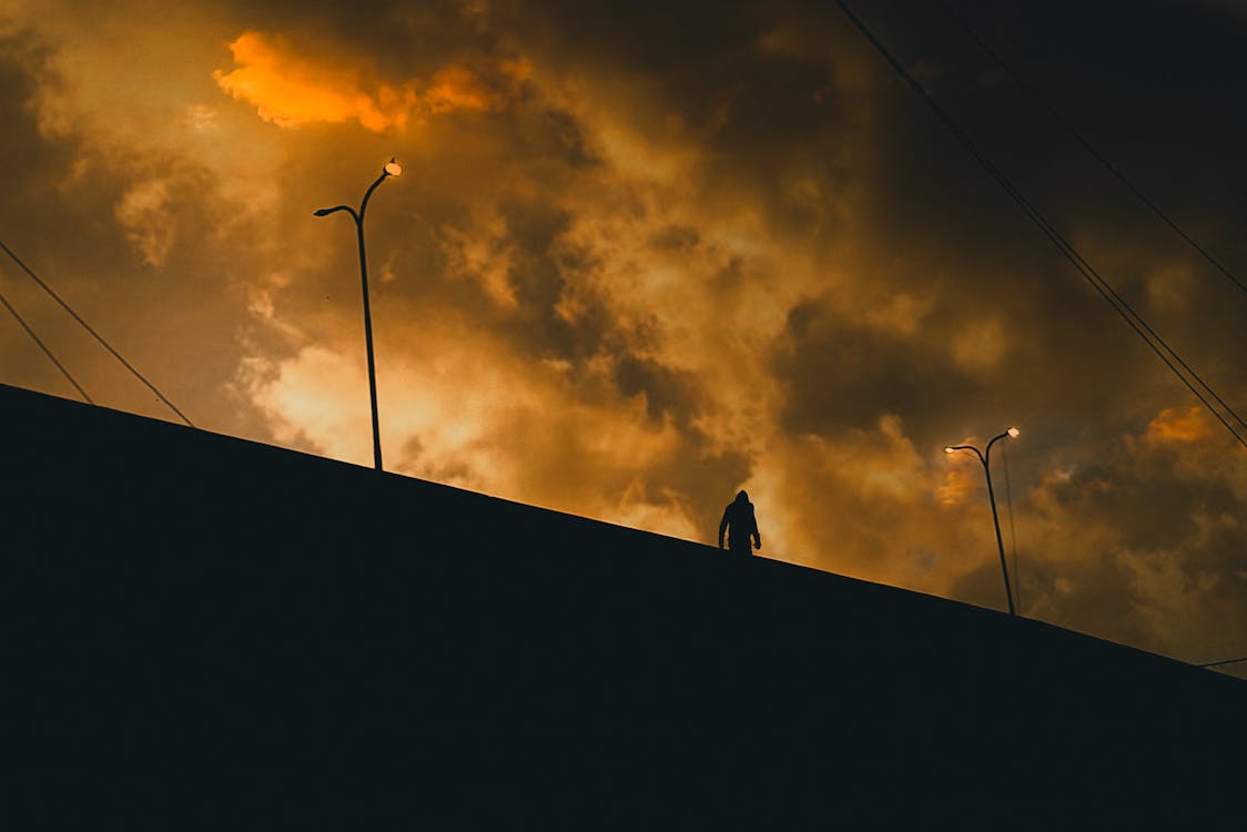 Silhouette of Man Under Cloudy Sky in Low Angle Photography 