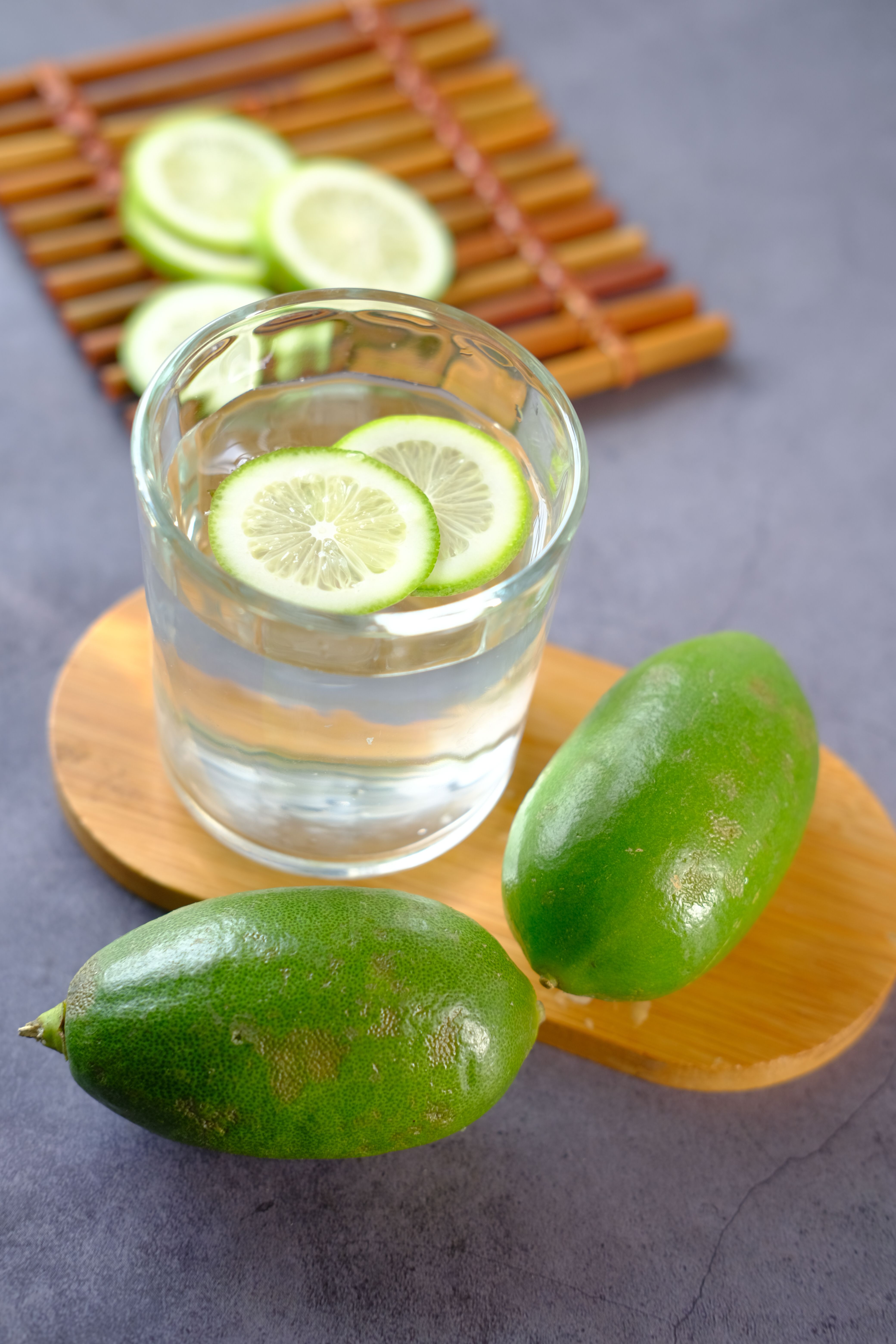Glass of refreshing lime-infused water with fresh lime slices on a bamboo board.