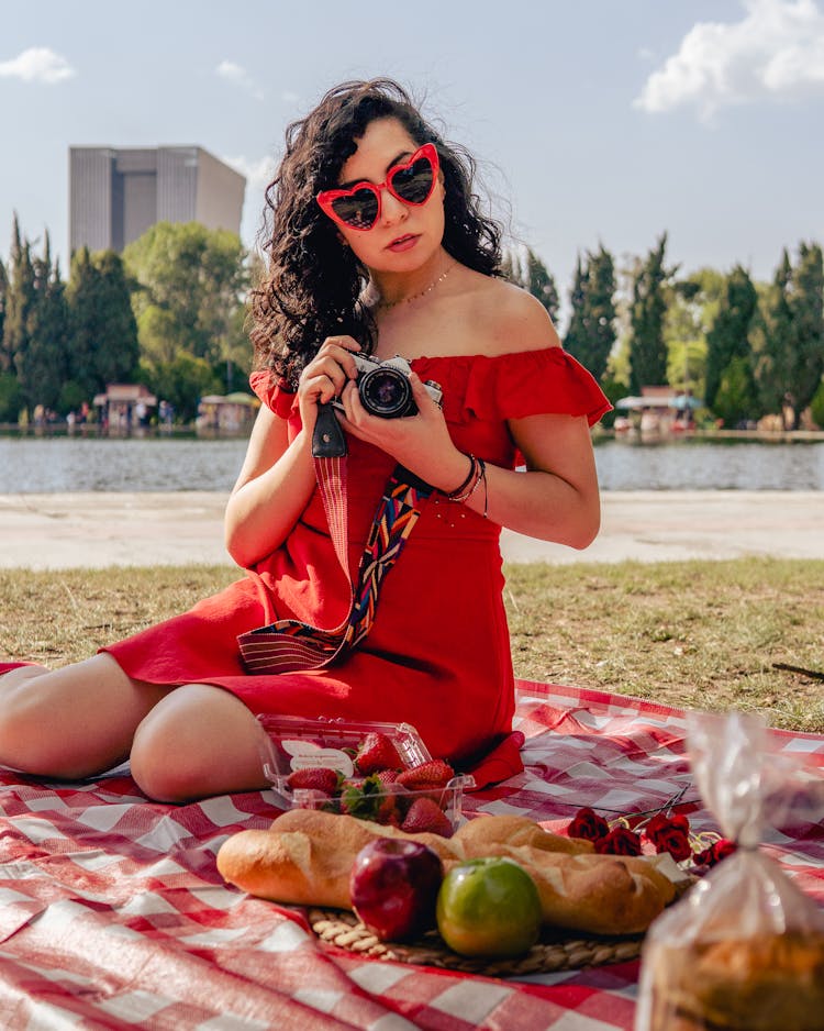 A Woman In Red Off Shoulder Dress And Red  Sunglasses Holding A Camera