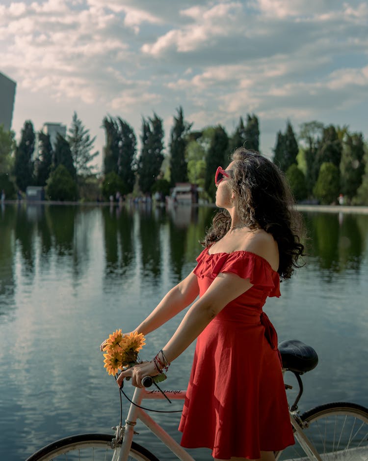 Woman With A Bike Standing Beside A Lake