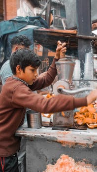 A young boy squeezing fresh orange juice at a street stall in Kolkata, India.