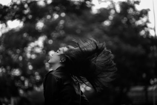 Artistic monochrome portrait capturing the dynamic movement of a hair flip against a blurred background.