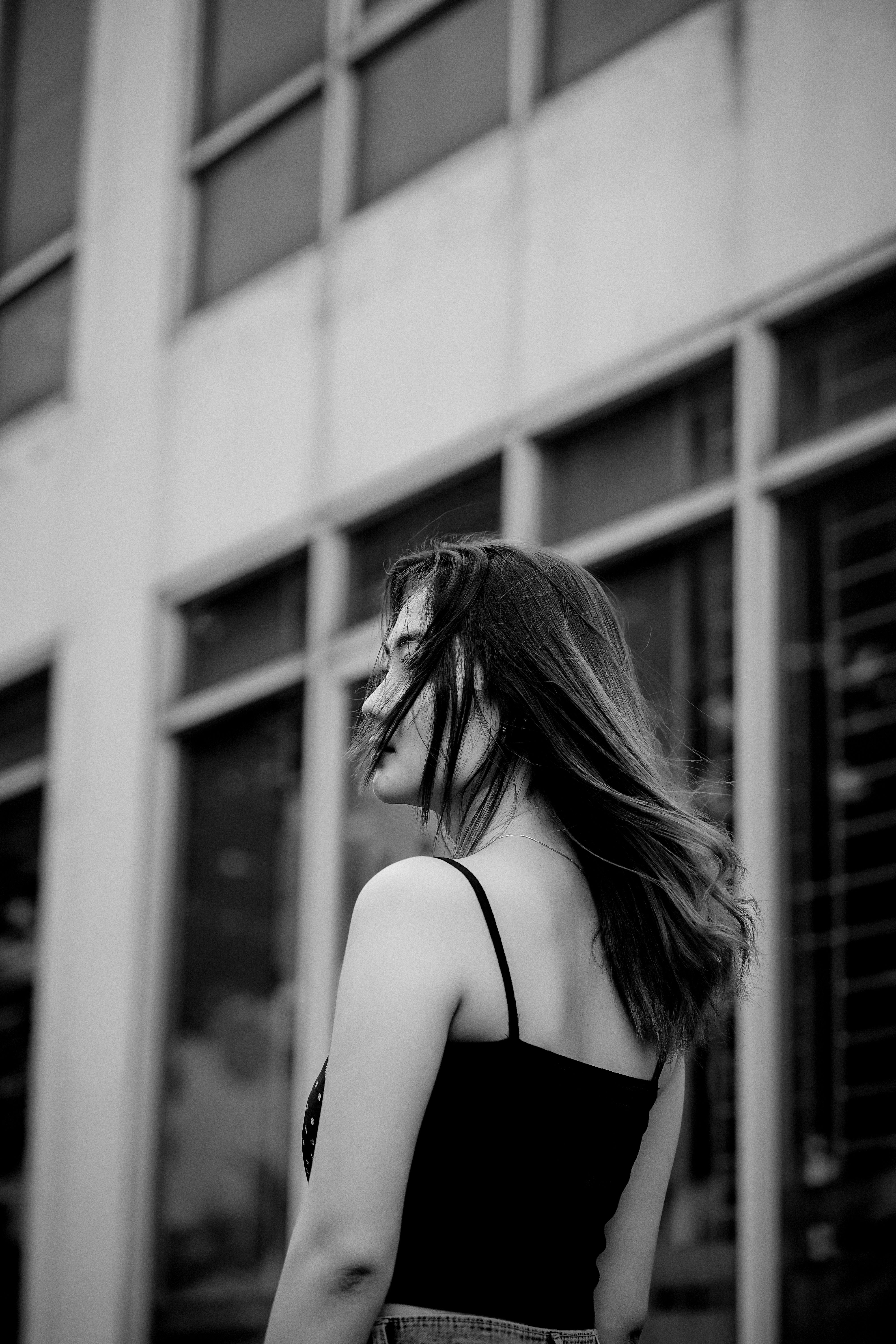 Elegant black and white portrait of a woman standing in front of a city building.