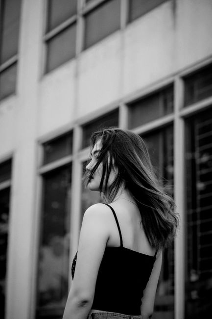 Elegant black and white portrait of a woman standing in front of a city building.
