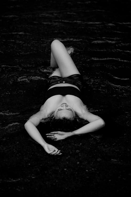 Woman in Black and White Bikini Lying on Water