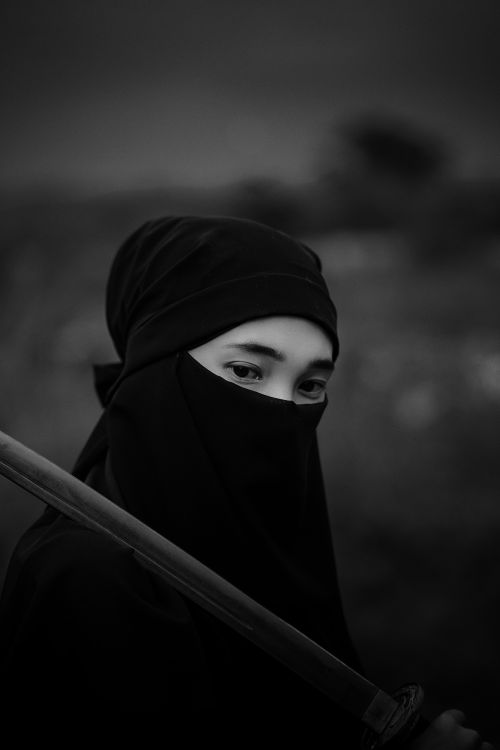 Free Striking black and white portrait of a person in a headscarf holding a sword. Stock Photo