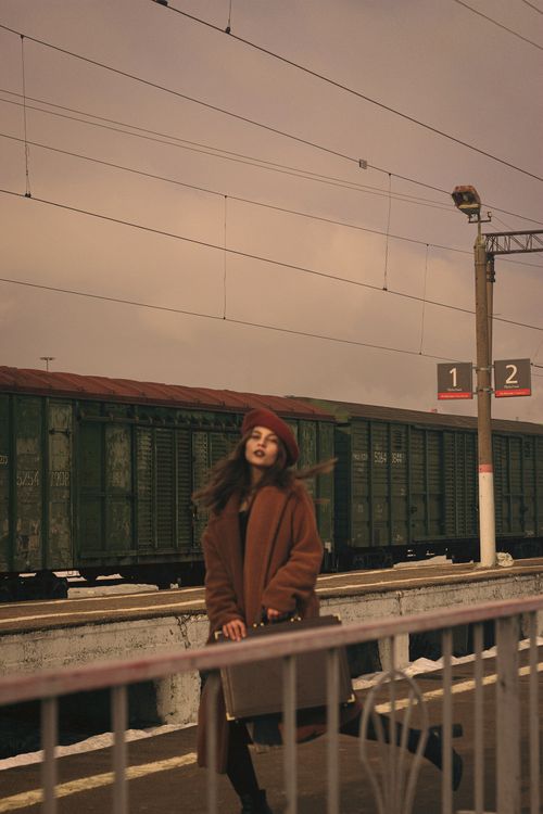 Free Elegant woman in a brown coat waiting at a Moscow train station, evoking a vintage vibe. Stock Photo