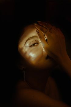A close-up portrait of a woman posing with hand on face, artistic lighting.