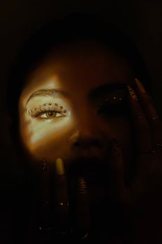 A moody portrait of a woman with striking eye makeup and creative lighting.