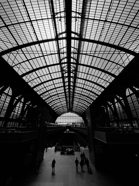 Grayscale image of Antwerp Central Station's intricate architecture with people walking.