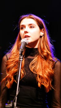 Energetic young woman singing passionately into a microphone on stage.