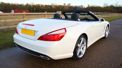 A White Mercedes-Benz SL with the Roof Down on a Road in the Countryside 