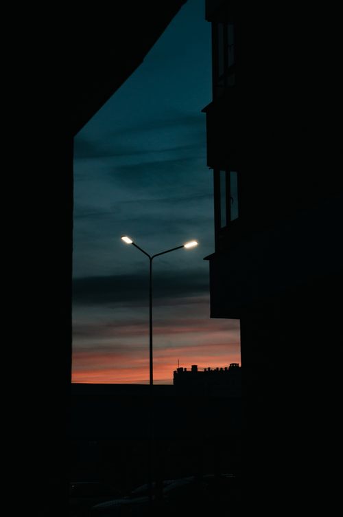 Free A striking urban sunset scene with silhouetted structures and illuminated street lamps. Stock Photo