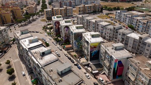 Free Aerial view of colorful street art murals on apartment buildings in an urban setting. Stock Photo