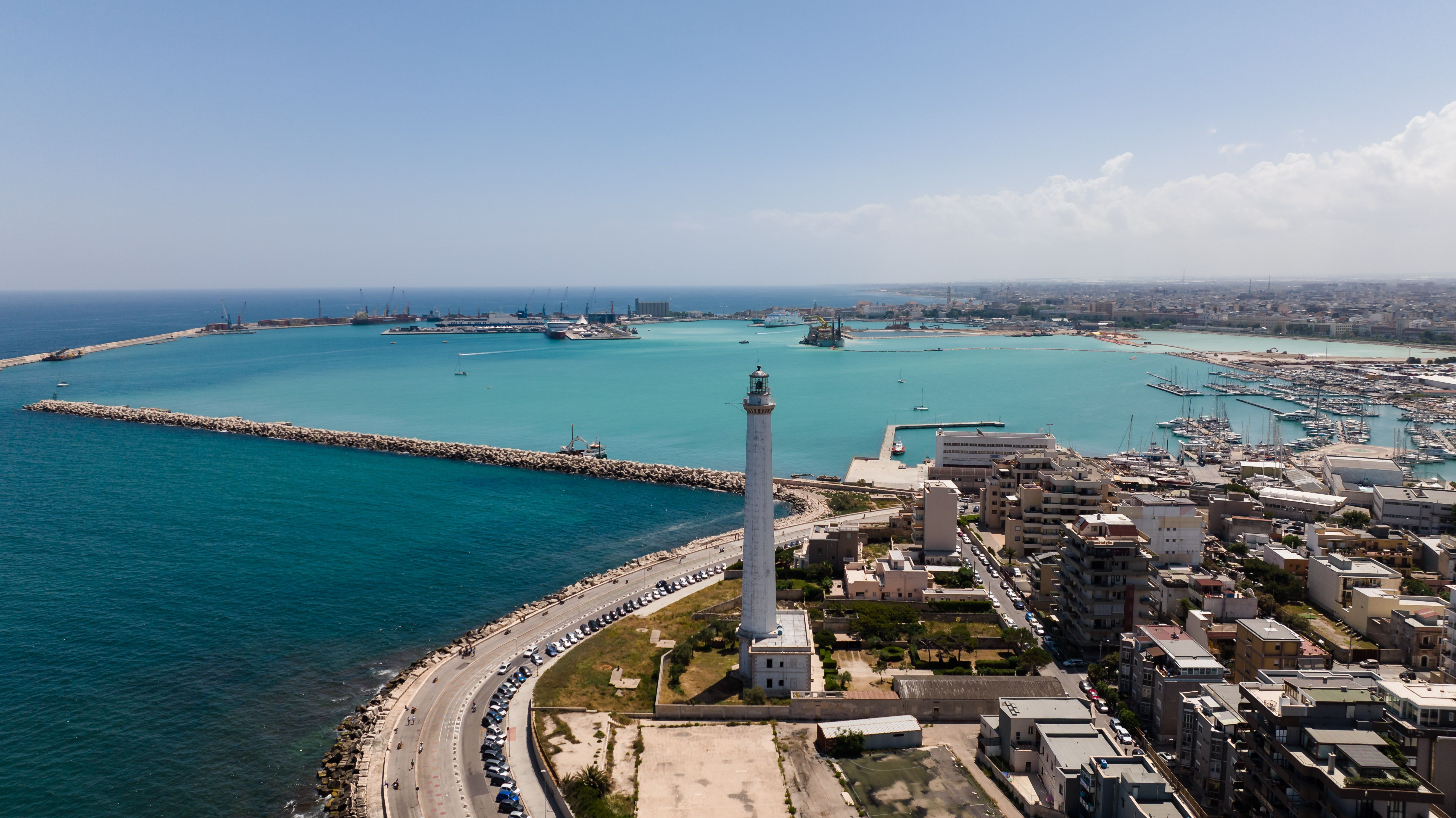 A stunning aerial view of a coastal city with a prominent lighthouse by the turquoise sea. - Bari