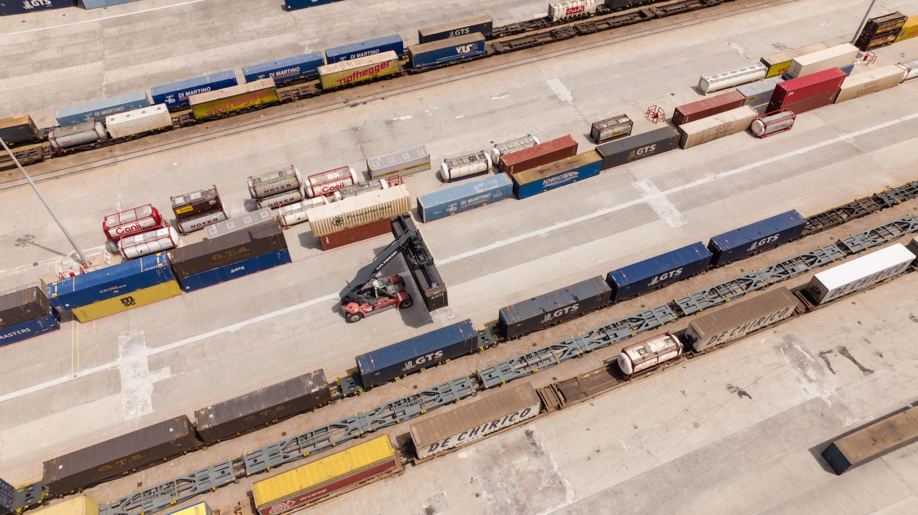 An aerial view of a busy shipping container yard with rows of stacked containers
