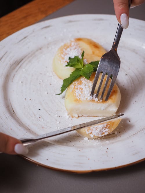 A Person Cutting a Round White and Brown Food