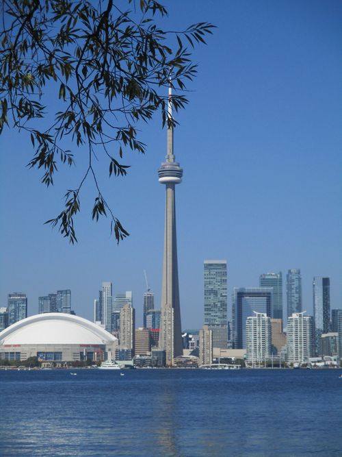 Free Iconic Toronto skyline featuring the CN Tower above the waterfront and skyscrapers. Stock Photo