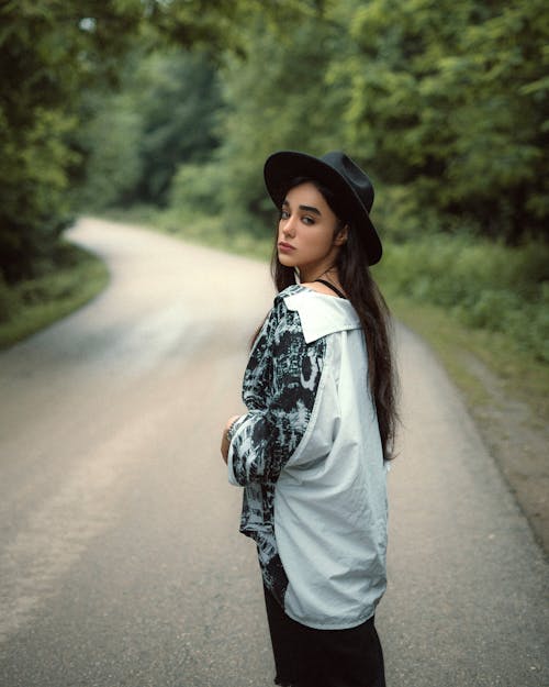 Woman in Black and White Long Sleeve Shirt Standing on Road