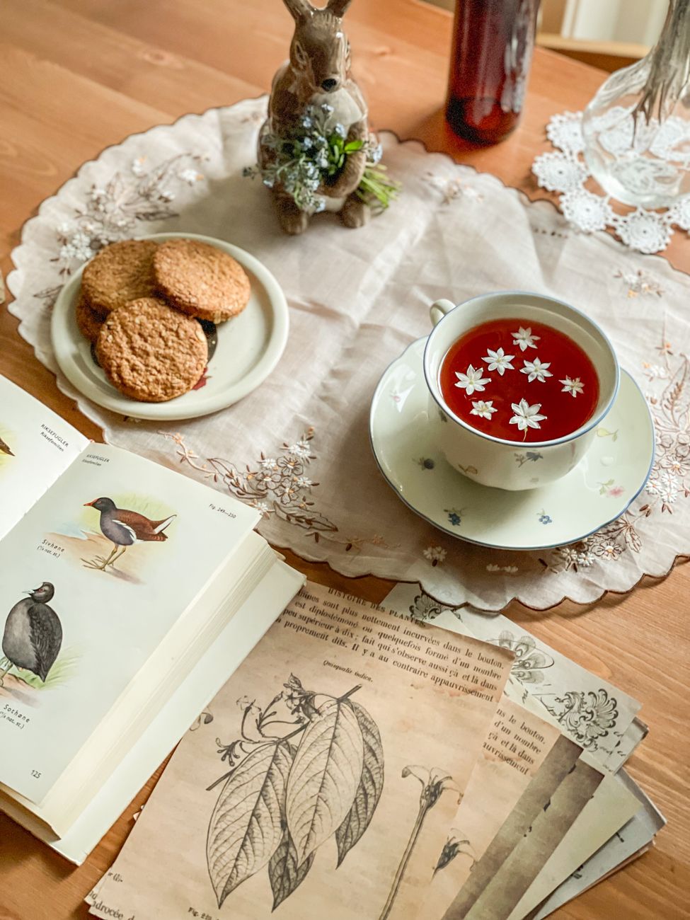 Cozy tea setup with floral tea and vintage botanical prints on a wooden table.. cozy, setup, with