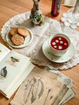 Cozy tea setup with floral tea and vintage botanical prints on a wooden table.. cozy, setup, with