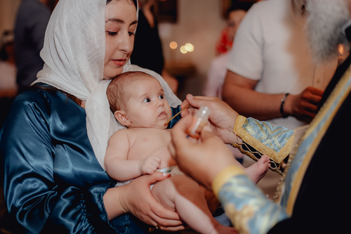 Free A mother holds her baby during a religious ceremony, capturing a tender family moment. Stock Photo