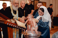 Man in Blue Dress Shirt Holding Baby in White Dress