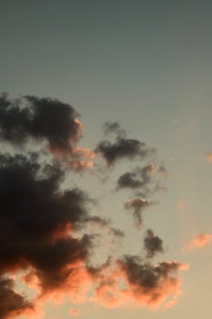 A vertical shot of a dramatic sky with dark clouds illuminated by twilight hues.