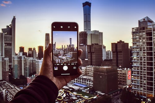 Person Holding Smartphone Taking Photo of High-rise Buildings